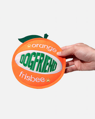 Hand holding an orange-shaped fabric dog flying disc