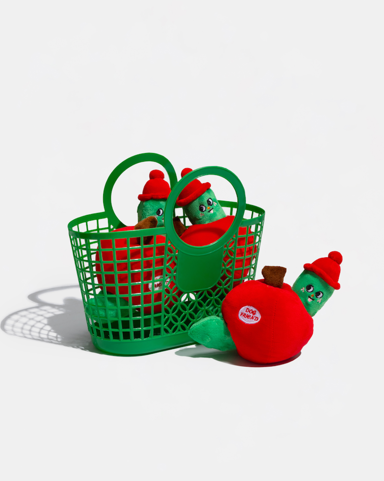 Apple plush dog toys with green worms in and beside a green basket