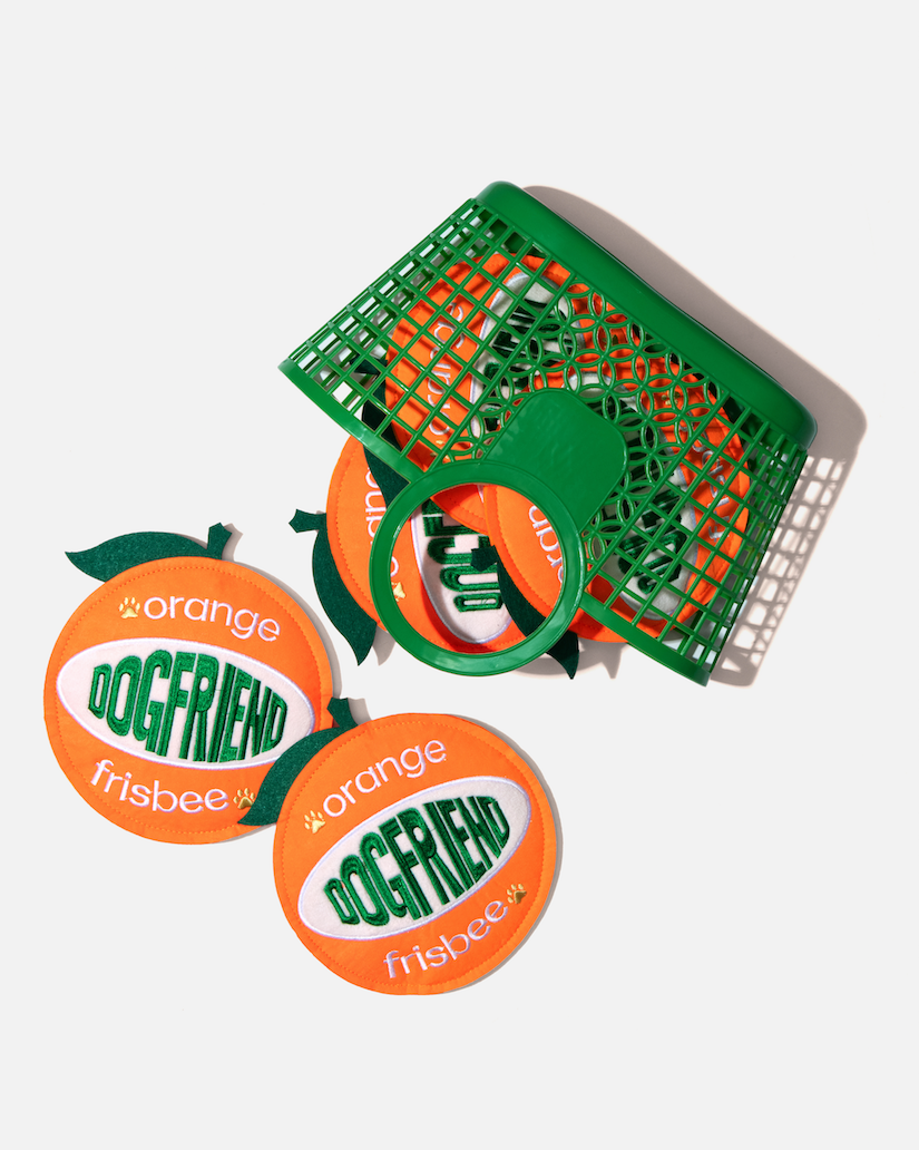 Orange-shaped dog flying discs spilling out of a green basket