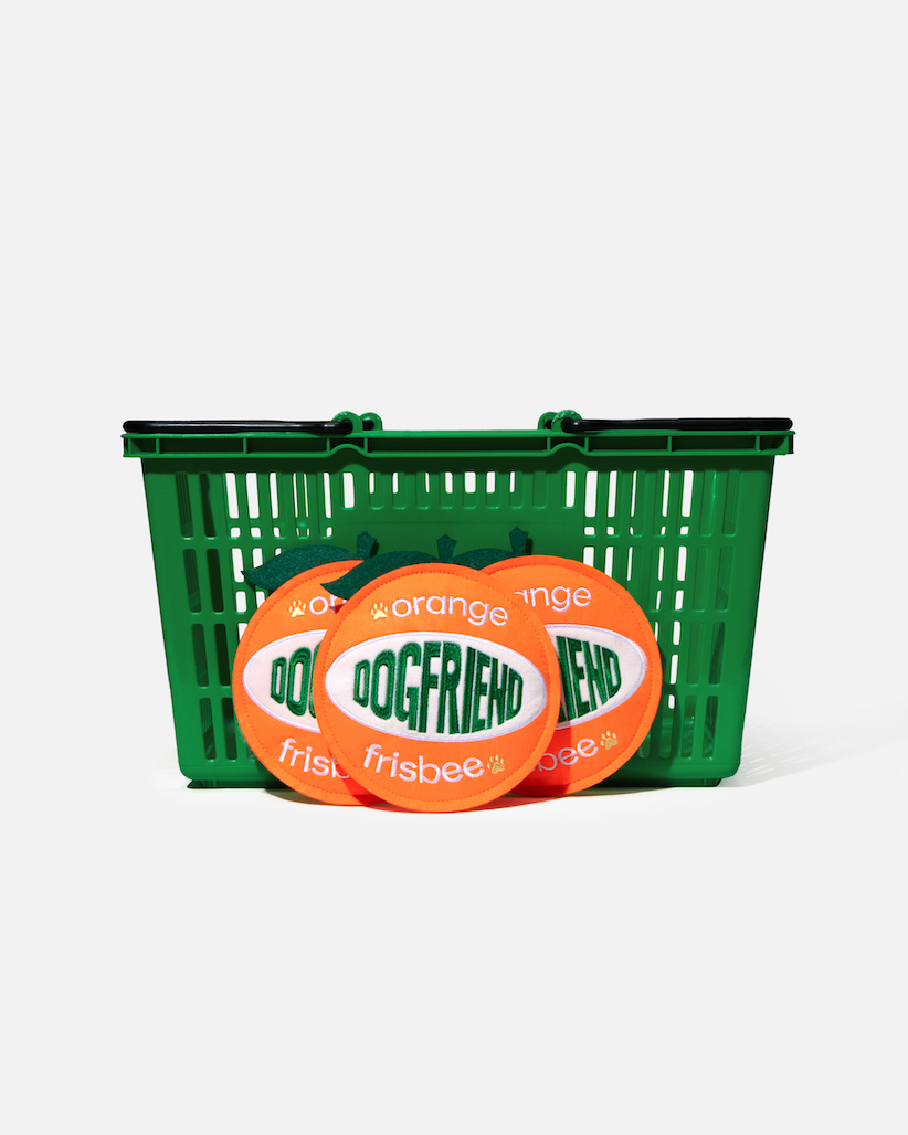 Three orange dog flying discs in front of a green basket