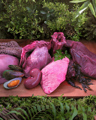 Raw meat, organs and mussels arranged on a board
